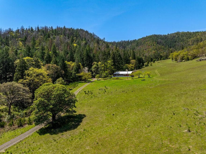 Nature Lover's Paradise with Owner Financing at just 4% Interest! This stunning 168 acre retreat is tucked into the peaceful Foothills just outside of Talent—only 15 minutes from town—offering the perfect blend of privacy & convenience. The home features 3,432 sq ft of living space, ideal for large families, multi-generational living, or creative use. The main level includes 3 bedrooms, a full bath, a charming country kitchen, & a sunlit living room with a cozy woodstove. The fully finished 1,608 sq ft basement adds 3 more bedrooms, a 2nd bathroom, & a spacious family room. Oversized windows showcase the beautiful views of open meadows, rolling hills, & forested areas. A reliable well & a private spring supply fresh water, while fruit trees, flowers, and wildlife like deer & turkeys add to the charm. Whether you're dreaming of a garden, orchard, or a peaceful sanctuary, this land is ready for your imagination to take root. This is a rare opportunity to create something truly special.