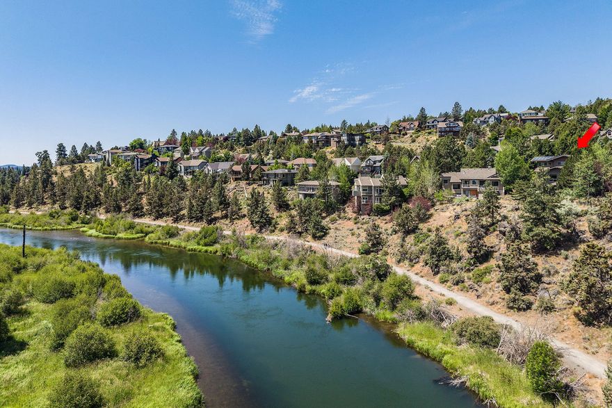 Perched above the Deschutes River Trail, this Westside Bend home showcases panoramic river views and seamless indoor-outdoor living. A verdant walkway leads to the entry or around to expansive outdoor spaces. Inside, the open great room frames the river and treetops in every season. The kitchen offers an island with seating, a large pantry, and abundant storage. Guest suites are on both the main and upper levels, where you'll also find an office nook and a spacious primary suite with a luxury bath and hot tub deck. The lower-level bonus room opens to tiered private patios with a fire pit and sweeping views of the river plus a front row to the Pilot Butte fireworks show! Tucked at the end of the street, the property features an oversized driveway for up to six cars, plus a 3-car garage ideal for a shop. From your door, stroll down to the river trail and parks, float the river, walk downtown and embrace the best of Bend living.