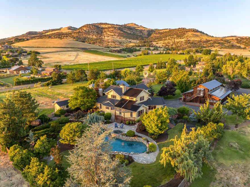 Located between Ashland and Medford, 4050 Royal Crest sits in one of the region's most desirable rural areas. The centerpiece of this 34-acre property is a custom farmhouse-style home that is full of character, with warm finishes and multiple living and dining spaces. The updated kitchen features a large island, great views and professional-grade appliances. The primary suite features vaulted ceilings with wood beams, a woodstove, incredible views, and a large private bathroom. Designed for indoor-outdoor living, the home opens to a brick patio, pergola, custom pool, and mature landscaping. Outbuildings include a three-car garage with additional utility spaces and a rustic barn with charming upstairs guest quarters. Currently a producing pear orchard, the irrigated land is primed for vineyard conversion, equestrian use, or as a small ranch. Gravity pressurized TID Water Rights. A rare blend of location, infrastructure, and potential, all framed by panoramic views of the Rogue Valley.