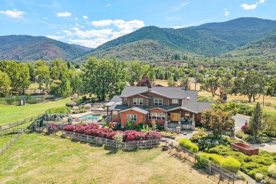 Nestled in beautiful Ashland, OR, this exceptional estate spans nearly 13 acres, offers stunning mountain views, and was completely remodeled in 2005. The main home boasts 4 bedrooms and 4 baths, with exquisite wood floors, custom hardware, and granite countertops. The kitchen features top-of-the-line appliances, including a double oven, perfect for everyday meals or entertaining. The generous primary suite includes its own cozy fireplace, jetted tub, and spacious walk-in closet, ensuring both comfort and functionality. Outside, relax or entertain by your private in-ground saltwater pool. Two barns and a covered arena provide ample space for equestrian pursuits or other hobbies. A full rec room with kitchenette and bath makes this property ideal for those who value space and versatility. This home offers an extraordinary lifestyle, blending luxury, functionality, and natural beauty!