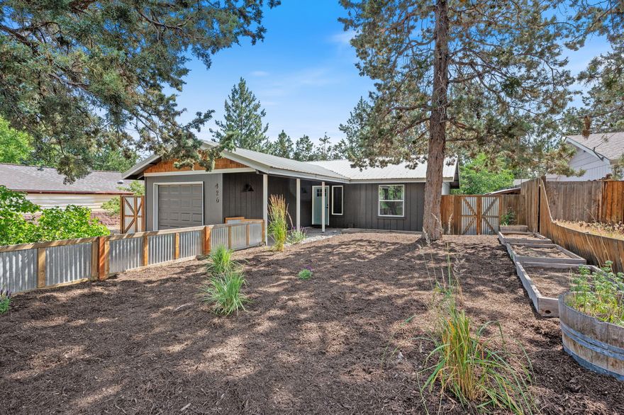 This well-kept 2 bed, 1 bath home is located in the heart of Bend! With fresh interior and exterior paint, new carpet, and an open layout, it is move in ready. The living area features vaulted ceilings and a wood-burning stove that adds both warmth and character. The kitchen includes custom open shelving made from reclaimed wood from Bend's original Old Mill. The spacious primary bedroom offers his and hers closets, and the second bedroom is perfect for a guest room, office, or kids room. Outside you will find a fully fenced yard with beautiful quaking aspen trees and native landscaping. An attached garage adds convenience for storage and off-street parking. The raised garden beds and small chicken coop are ready to be used! Covered entryway and back deck offer plenty of outdoor spaces to relax. Property is zoned RM which could provide flexibility for future options. - buyer to verify all uses.