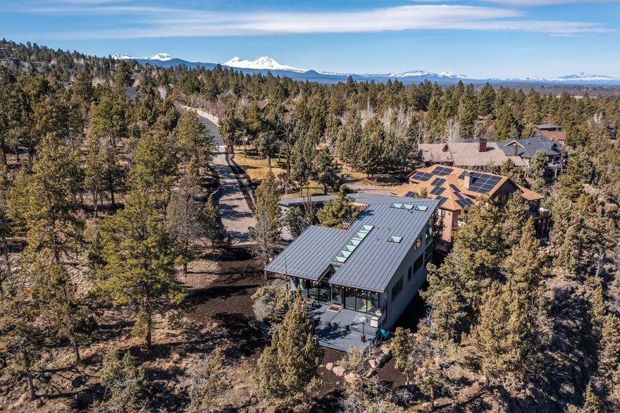 Entered for comp. Iconic custom modern home perched above the Deschutes River with 180-degree views from Pilot Butte to Smith Rock and Mt. Hood. Destined to be the center of your recreation hub with easy access to river trail, golf, and more. Heated paver driveway, metal roofing, soaring interior spaces, walls of windows, central vac, & remote window shades enhance your everyday. The heart of the home offers luxury Thermador appliances, exposed beams, contrasting countertops, & new Ann Sacks tile backsplash. Shadow and light playfully illuminate the great room with wet bar, custom built-ins, & floor to ceiling fireplace. Host family & friends on the view patio with outdoor kitchen or relax apres-ski in the hot tub under the stars. Main level primary suite, den/flex room, plus tandem 4-car garage with EV outlet are appreciated amenities. Call this your Bend home and live your best Bend life!