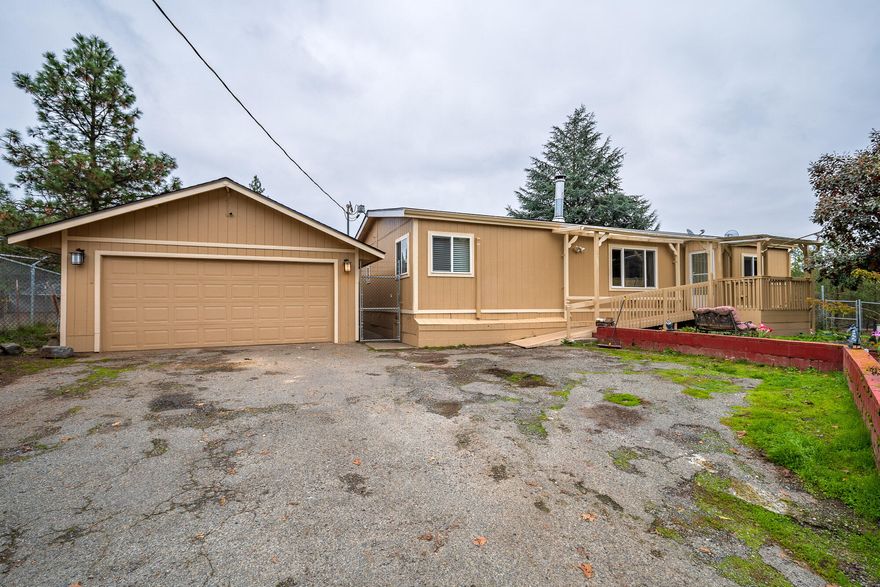 Mini farm in the country! Mostly level 5.05 acre property fenced and cross fenced with a rustic old barn . This could be a great new setup for your horses, goats, pigs, etc.  Built in 1990 this manufactured home has had many recent improvements including: exterior paint, composition roof, in Nov. 2021, and bathroom remodels. A desirable split floor plan with a primary bedroom with en-suite with new vinyl flooring and tile shower. Plus two additional bedrooms and guest bathroom with tile shower.  The living room has vaulted ceilings and is warmed by a wood burning stove or mini-split system. An open and spacious kitchen leads to an indoor laundry room w/ washer & dryer included!  Enclosed back deck, detached two car garage also contains a half bath and extended space great for storage. Two newer Premier Tuff sheds w/ smart floors will be included w/ the property. Newer well pump in 2019 & Mini-split in 2017. Low county taxes, one mile to the River & just a 15 min drive to Grants Pass!