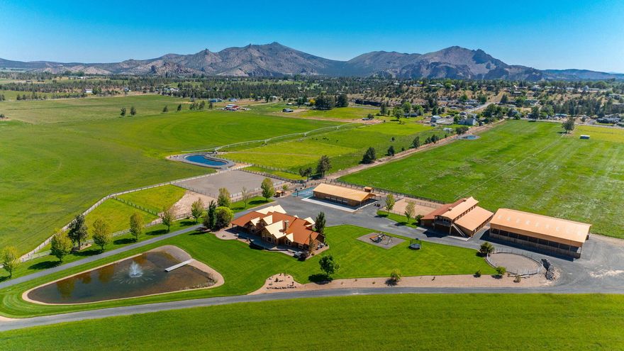 Sprawling hay fields frame this custom home with majestic 7 peak Cascade Mountain views to the west and Smith Rock views to the northeast. A custom NW lodge style home with high end finishes uses every vantage point to soak in the views from just about every room. All bedrooms are ensuite with the primary and a guest suite on the main level. Enjoy evenings on a covered porch over-looking the swimming pond & fountain with the mountains as your backdrop. The outbuildings are as elevated at the home, a spacious 9 stall barn with wash stall, grooming area, office, tack room and a recently added spacious ranch hand apartment. There are turnouts, round pen and riding arena. With a 6300+ sq ft 4 bay shop with an office you will have plenty of room to store work and play vehicles. Property is income producing through hay production. The 8600 sq ft covered hay storage can easily be converted to a covered ridding arena. If it all sounds too good to be true, it's not! Come see for yourself.
