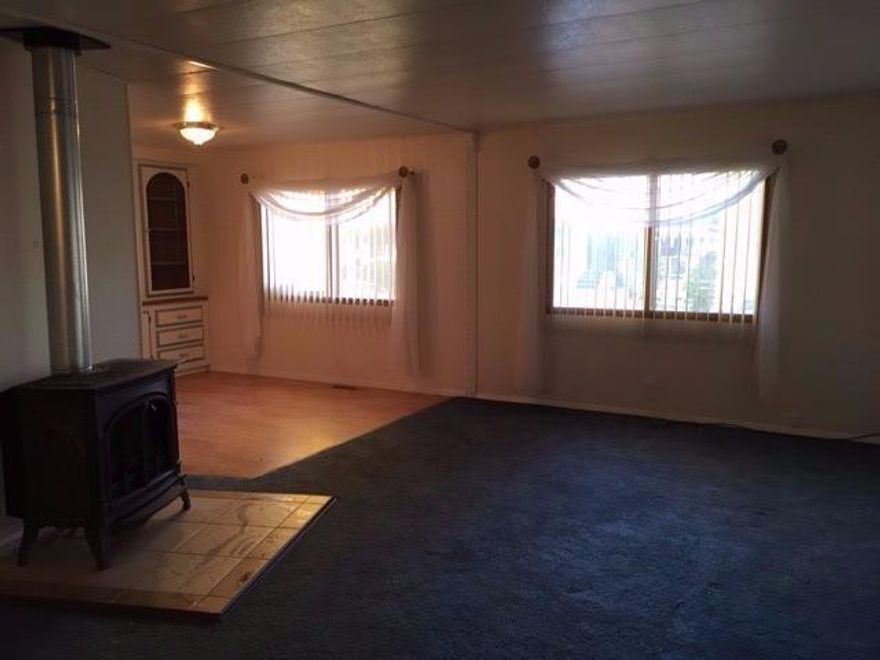 A nice, roomy 3 bedroom, 2 bath Mobile Home cleaned and ready for it's new owner. All appliances are included in the spacious kitchen. Some upgrades were done, including new siding, new roof (approx 2008) two tone paint on the cabinetry & laminate flooring in the dining area. The living room has newer carpet, blinds, curtains and a wonderful gas stove, with tile surround, for extra warmth. Nice fenced yard for your small pet (approval from manager required), and nice size shed for storage. This is a 55 + park, but might work if you are 45 +.