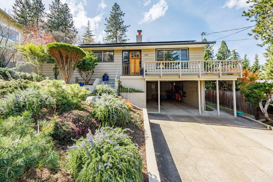 Modest exterior on quiet street opens into a sunny, expansive home gracefully combining open floor plan with private spaces. Large windows in the spacious living room capture the views; relax by the lovely gas fireplace/stone hearth. Adjoining dining area opens into the spacious kitchen with vaulted ceilings, chef's cooking island, abundant cherry cabinets and stone floor that extends via double-wide glass sliders onto dreamy patio. Expansive deck, what views! Main level primary BR suite has wood floors, private deck, spa-like bath w/jetted tub & stand-alone shower. Down the hall 3 more BRs plus bath, perfect for children or home office. Daylight basement boasts separate entrance, fireplace, huge family room, 3rd full bath, bonus space and kitchenette - perfect for overflow living (teens, nanny, in-laws). Solar panels, newer water heater, great workshop space in the carport. Beloved & well maintained by just two owners in 60 years; all the warmth & functionality you need.