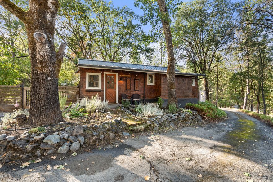 Beautifully maintained and minutes from the Rogue River, this 3-bedroom, 1-bath, 1,123 sq ft home is filled with charm and thoughtful updates. The inviting living area features hickory hardwood floors and a propane fireplace with wood and herringbone tile detail. The kitchen offers a small pantry, a spacious island ideal for gathering, and a bonus room provides the perfect space for an office or library. Recent upgrades include a durable metal roof, newer water heater, well pump, holding tank, interior paint and efficient mini splits. Outdoor living shines with a paved driveway, cedar shingle siding, a relaxing deck, front-yard sprinklers, and numerous fruit trees across 1.75 acres of landscaped, gently sloped terrain. RV parking, A 1-car garage with a bonus room and 220 power plus a detached shop or storage building add flexibility—with possible ADU potential. A rare blend of comfort, function & natural beauty.