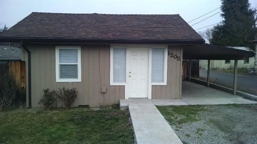 Sweet little doll house has new roof & gutters, new flooring, some new plumbing, new kitchen cabinets, new double-pane windows - $50,000+ in recent renovations. Was 2 bedrooms, but now a big open 1 bedroom suite, 1 bath plus a cute little dining nook and separate laundry room. New cement walkways and in the carport and back porch areas. City recently installed storm drains and paved the alley. Lots of room off the alley to build a shop or garage behind the house. Check with city of Medford for other possibilities in SFR-10 zoning. Charming original high ceilings and moldings add to the feeling this is a much larger home than it looks. Newer water heater (electric) as well.