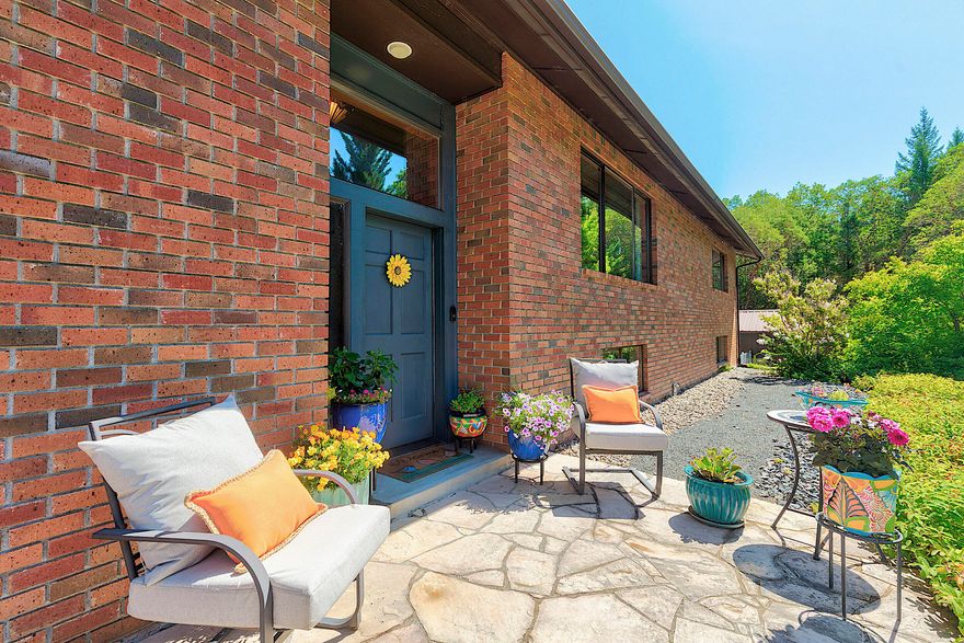 Tucked away in a serene setting off the road, this stunning split-level brick home is the perfect blend of elegance, comfort, and privacy. The main level offers 2175 SF of bright, open living space. It features a welcoming living room with fireplace, a chef-inspired kitchen with granite counters, oversized island, newer appliances, Italian tile floors and custom blinds, and a large dining area that's perfect for entertaining. The generous primary suite is a true retreat with a walk-in closet and a newly updated bathroom with private sauna. An additional guest bedroom and updated bathroom complete the main floor. Downstairs, enjoy over 900 SF of living quarters with a bedroom, living room, half bath, workout room, and laundry area. Outdoors you'll find a fenced yard, raised garden beds, pear and plum trees, and a beautiful back patio with tranquil water feature. Plus, there are two single car garages. This property delivers on space, style, and a sense of sanctuary! It's a must tour!