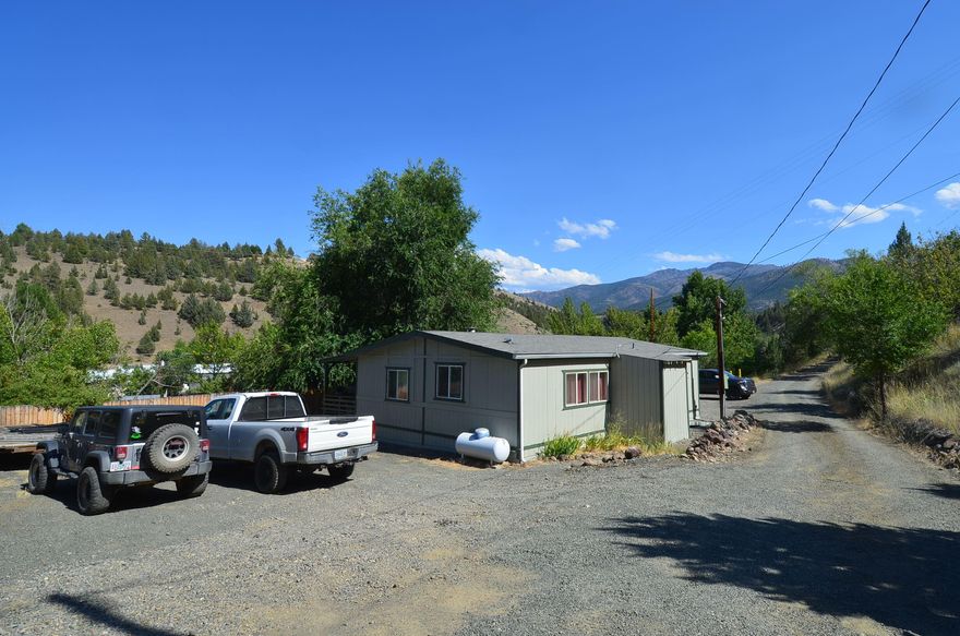 Welcome to this charming 1981 Parkway manufactured home, situated on a .91 acre lot with beautiful views and plenty of parking. This cozy home offers new laminate flooring throughout the main living space and a vaulted living room ceiling, creating a bright and airy atmosphere. An open concept kitchen with ample counter space makes cooking a breeze. The home also boasts two bedrooms, two bathrooms, and a laundry room. Outside, a 24x24 shop with concrete floors, man door, garage door, 220 power for an RV and an insulated storage room provides plenty of storage options. The .91 acre lot includes a large parking area, city water, septic tank, and a covered back deck which provides a great spot to enjoy your view. Vinyl windows throughout the home add to its efficiency. Propane on demand hot water heater. Fresh exterior paint.