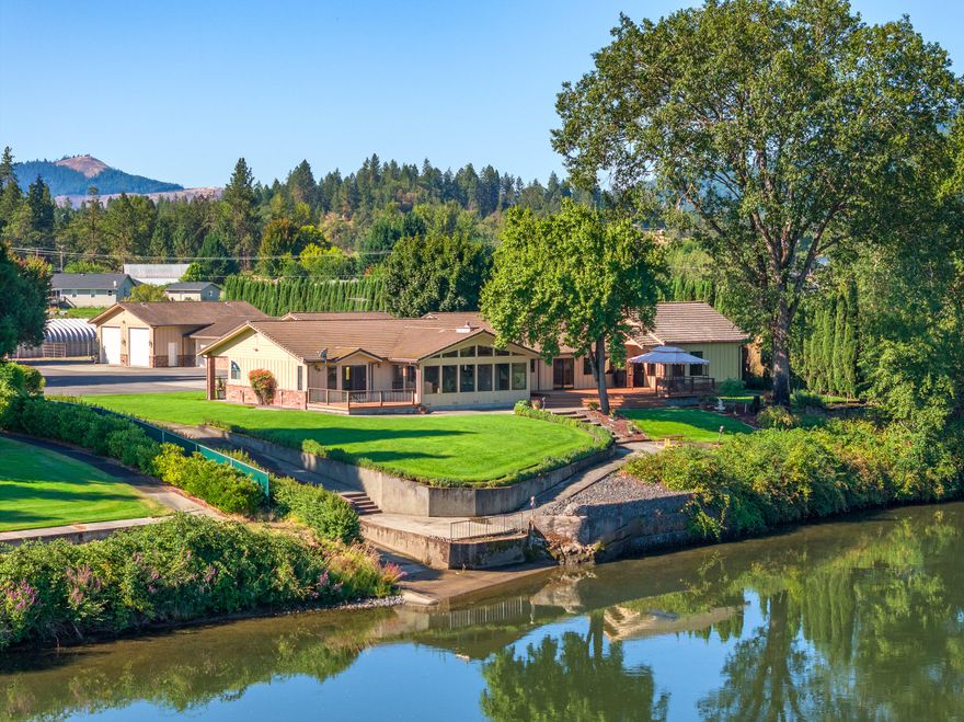 Rogue Riverfront in Grants Pass. Boat ramp, gated, private drive leading to well appointed estate on the river. This property has a little bit of everything for everybody. Perfect for a river/fishing enthusiast, hobby farmer, workshop/metal shop, rent the pastures or workshops as potential for income generation. Enter to a breathtaking river/mountain view out the panoramic windows in oversized living and dining room. The primary bedroom suite has its own deck leading to the landscaped frontage. The kitchen has classic lines and space for cooking and entertaining. 2 large bedrooms, game/family room with wet bar, 3 car garage with loads of storage. The RV garages, huge workshop/business opportunity has plenty of storage and utility space, 220V service, air compressor, SO MUCH MORE! A private entrance leads into an enormous room that could be a 2nd primary or rented. Use the pastures for your animals.  Qualified Buyers Welcome .