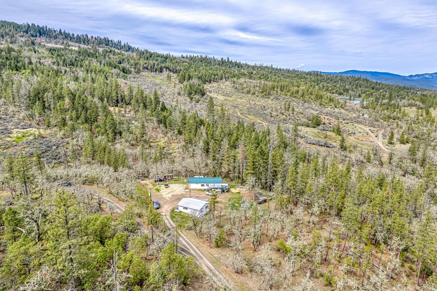 Enjoy modern living in the beautiful mountains of Trail, Oregon! Located on a sprawling 30.24 acres & nestled in the quiet hills, this property offers plenty of seclusion & space while only being a few minutes from town. Access this adorable 3 BD, 2 BTH home through an automated private gate & immerse yourself in picturesque wooded land with breathtaking views. The house boasts a thoughtfully designed split floor plan, large living room, vaulted ceilings, & cozy wood stove! The gourmet kitchen is spacious & has ample cupboard/counter space, new vinyl flooring & a mud/laundry room attached. The primary bedroom is complete with an adjoining ensuite & walk-in closet! Enjoy multiple decks, a storage shed, covered wood storage, detached 2-car garage, & ample room for RV parking. New features over the last 1.5 years include: well pump, holding tank, filter system, septic pump, smart thermostat & electronic door lock! Claim this mountain property as yours, call to schedule a showing today!
