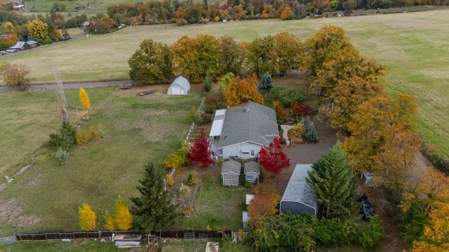 Classic 1965 ranch-style home, located on 2 irrigated acres in Talent's rolling foothills. Surrounded by vineyards, orchards, and open pastures. This 2,240 square foot home features 4 bedrooms and 2.5 baths, offering comfortable country living with plenty of room to grow. The home showcases solid red oak floors in the kitchen and living areas, a strong well with a multi-stage filtration system, and a brand-new HVAC installed in 2024. Outside, the property is set up for small-scale farming or hobby livestock, with a fenced pasture, barn/shop, mature fruit trees, and a peaceful koi pond. Eastern views and fertile ground make this an ideal mini-farm for those seeking self-sufficiency, space, and rural charm. Just minutes from Ashland, enjoy quick access to world-class theater, dining, boutique shopping, outdoor recreation, and the vibrant cultural arts scene that makes the area so special — all while still savoring the peace and privacy of country living.