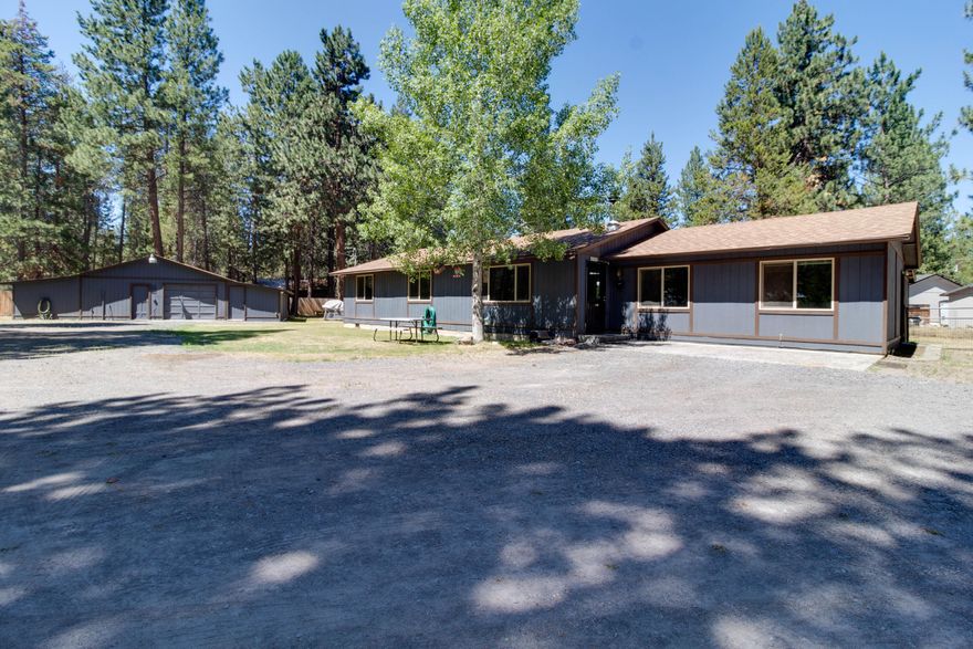Nicely located on fenced corner lot. Home has been well cared for with new roof and newly pumped septic.   Covered back deck with wood storage as well as storage for toys!  Attached garage was converted to a family room and extra bedroom, giving the home 4 spacious bedrooms. Laminate flooring throughout with carpeted bedrooms.  Living room has woodstove for those cold La Pine days and nights!  Interior home has been freshly painted.  Tile countertops in kitchen with ample cabinets.  Room for table off of Kitchen. Lots of storage throughout the home. Insulated attached Garage and workshop with woodstove, as well as two additions on sides of garage and workshop, both with electric.  Outdoor firepit with room for all your toys!!