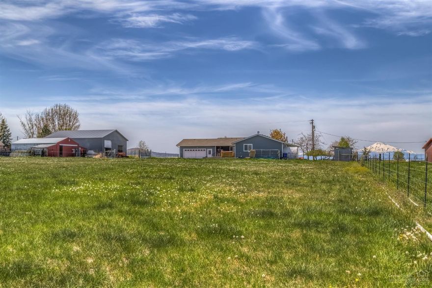 Cascade Mountain views, rare 4.98 parcel on outskirts of town. 3.1 irrigated acreage property has been updated within the last few years inside & out. Interior offers vaulted ceilings w/ wood accents throughout & in recent years has had kitchen & bathrooms remodeled. Exterior has been resided, re-roofed, as well as covered back porch addition w/ stamped concrete. Trex decking, oversized double car attached garage, 40x40 shop w/large door for RV, storage barn, fenced pasture, irrigation pond & fruit trees
