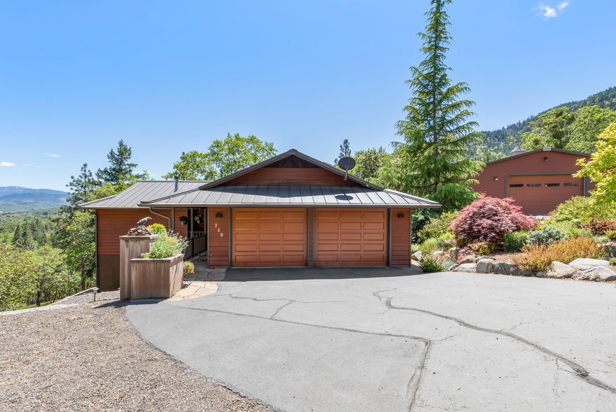 Dynamic country home on acreage, ~32x32' detached shop with 220v power, fully fenced ~5,500 SqFt organic garden with drip irrigation, temperature-controlled greenhouse with solar-powered electrical, and 10x20' shed — all only 10 minutes from town! Main level features walls of windows with stunning mountain and valley views, solid oak flooring, formal and informal dining areas, expansive cedar deck with gazebo, kitchen with stainless appliances, granite counters, skylights, master suite with walk-in closet and dual vanity, laundry and half-bathroom, and 2-car garage. Lower level includes two bedrooms with sliding glass doors, additional full bathroom, and ample basement storage. Exteriors with redwood and hardiboard siding, metal roofing. Well tested at 20-gpm, with 2,000 gallon holding tank, water softener, UV light, carbon, and sediment filter. Grounds with engineered rock retaining walls and terracing, new hot tub and fire pit, asphalt driveway, and hiking trails.