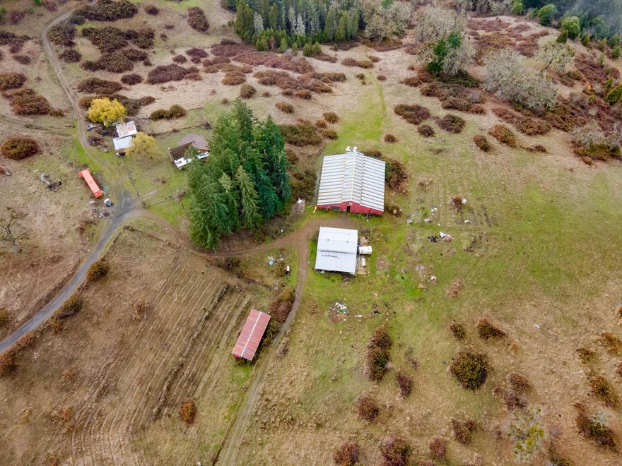 Escape to tranquility in this charming 3-bedroom, 1-bath log home, nestled in the heart of the Oregon mountains, just outside the peaceful town of Myrtle Creek. Offering 1,665 sq ft of cozy living space, this property is surrounded by rolling hills, majestic mountains, and absolutely no neighbors in sight—perfect for those seeking privacy, natural beauty, and the serenity of country living.Myrtle Creek, located in the scenic Umpqua Valley, is a hidden gem known for its friendly community and outdoor adventures. Surrounded by lush forests and pristine rivers, this area offers abundant opportunities for hiking, fishing, and exploring. While the town maintains a relaxed pace, you're still just a short drive from Roseburg and its amenities.This former working cattle ranch boasts impressive outbuildings, including a 90x90 feeder barn, a 50x40 second barn, a machine shed, and ample shop space. A large hay loft provides additional storage for farming or recreational needs.