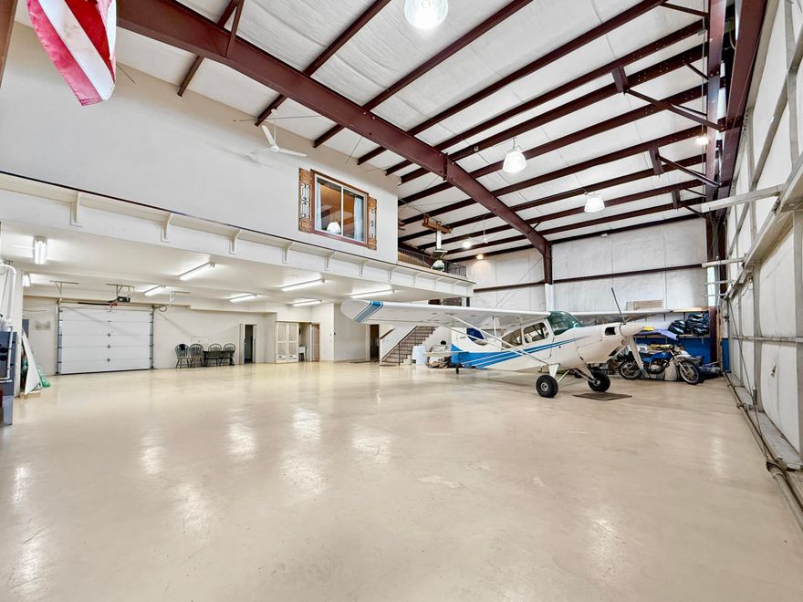 Rare fly-work-stay opportunity at Bend Municipal (KBDN). Approx 5,400 SF under roof with a fresh 37-yr ground lease. The 60' × 60' footprint (plus 150 sf bump-out) blends a Wilson bi-fold door (12' clear) hangar bay and an integrated large main-floor office & full bath. Front side offers an 8' roll-up for pull-through access. Interior RV hook-up/dump. In 2001 a ±1,650 SF mezzanine became refined crew quarters: hardwood & tile, full kitchen, dining, expansive living area, two bedrooms, and a patio overlooking the bay with sweeping Cascade views. Robust climate control with forced-air natural gas, two high-efficiency heat pumps providing both heat and A/C, a dedicated Reznor gas heater in the bay, and ceiling fans throughout. Abundant cabinetry keeps gear organized. A distinctive chance to fly, work, and stay at Central Oregon's most popular GA airport—contact listing broker for full details.