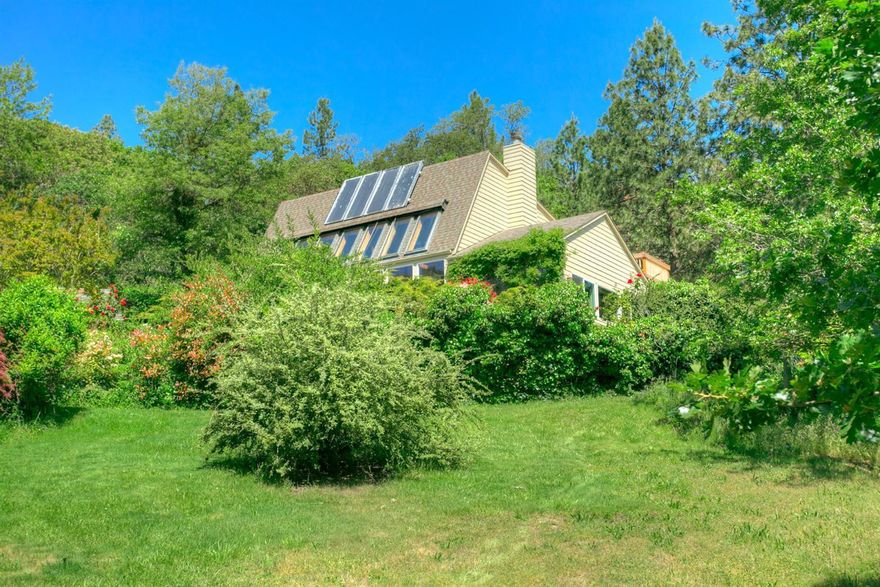 One of the prettiest settings in the valley. Located just a few minutes outside of Jacksonville, this 5.32-acre parcel has lovely large open sunny meadows, grape arbor, fenced large garden, small seasonal pond, orchard with cherry & apple trees, wooden walkways meander through picturesque grounds & in the distance large pines. The grounds are like a fairyland. The views are expansive, beautiful & prominently feature Mt. McLaughlin. The home was custom built in 1982 & created to utilize solar heat for the living spaces. Solar sun room has 2 large vents that warm the main living spaces a well as cool air vents. There is a solar hot water ex-changer. Living room has wall of view windows, fireplace & passive solar Trombe brick wall. Good southern exposure. Corian counters in kitchen, jetted tub in master bath, office is plumbed for a bath, large landing area makes extra living space. 2 car attached garage, separate workshop & shed. 50 gallon per minute artesian well when drilled in 1980.