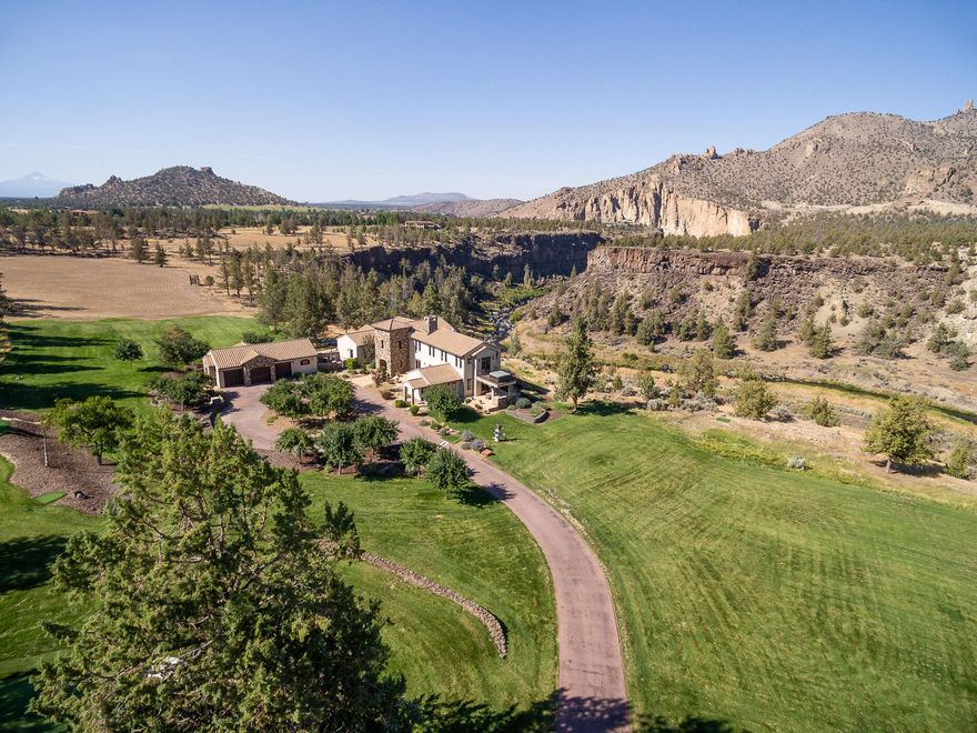 This Ranch at the Canyons luxury home overlooks Smith Rock and the gorgeous river canyon with a path directly to the river below. The grounds are lush and inviting with a professional grade putting green with 3 approach areas plus acres of verdant grass within the 13.5 total acres. The home is an elegant blend of wood and stone, vaulted ceilings and also cozy spaces. Primary suite options are on both levels, and a gorgeous office is just one of multiple work spaces. The gourmet kitchen features Wolf appliances, Viking hood, Sub Zero fridge and casual dining, and the adjacent tv room could also serve as formal dining. The subterranean wine cellar is a secret treasure. Enjoy the community's private  Clubhouse with pool & fitness center, tennis & pickleball, an event venue,  equestrian center and 1700 acres of fields, trails and ponds. All furnishings and quality commercial grade lawn mower may be included with the sale.