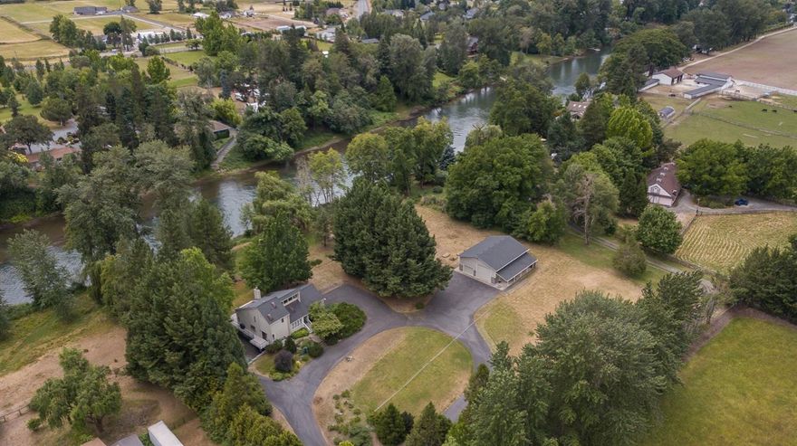 Private, gated, river front estate with irrigation rights on 2.6 acres. Views of the Rogue River, detached shop, circular driveway, hay field, a grove of fruit trees and more! Located on a deep part of the river, there is a fantastic fishing hole in your backyard. This 3 bed and 2.5 bath house boasts vaulted ceilings, and plentiful natural light. The kitchen has granite countertops, custom cabinetry, and stainless appliances. The master suite is on the second floor, has a private deck with river views, walk- in closet, and private bathroom. The two downstairs bedrooms are large; #1 has a walk-in closet and #2 has river views. Off the dining room is a large wrap-around deck for summer BBQ's and river views. Under the house is a five car garage with a workbench, and tons of storage. Detached, is a 1,750 sq ft shop with a 13' tall X 14' wide door and 100 amp service with 220V including a 30 amp RV hookup. The shop has plenty of storage, lighting and tall ceilings.