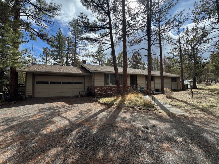 Tucked away on nearly 5 acres of flat, wooded land, this 4-bedroom, 2-bath home is brimming with original charm and endless potential. Featuring vaulted ceilings, cedar walls, exposed beams, and two cozy wood-burning fireplaces, this home is a true time capsule—right down to the green shag carpet and funky vintage light fixtures! Large picturesque windows flood the home with natural light and offer beautiful views of the surrounding trees. The spacious back deck is perfect for soaking in the peaceful setting. Inside, the small but functional kitchen is ready for a refresh, and the original electric furnace keeps things toasty in the winter. Key updates include a new concrete septic tank (2005) and relocated drain field, with the roof likely replaced around the same time. With its unbeatable location near Shevlin Park, this property is an ideal investment or renovation project for those looking to bring this retro gem back to life. Home sold AS-IS.