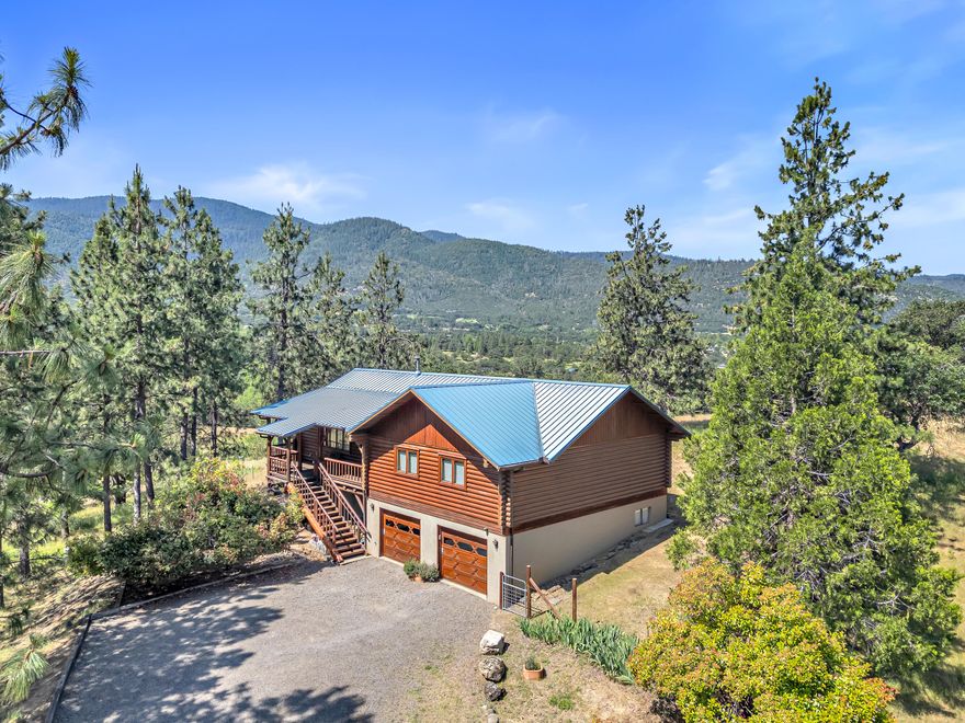 Rare opportunity in one of Ashland's most coveted neighborhoods! Just minutes outside the city, Corp Ranch Rd is a premier community of custom homes in the foothills of the Cascade-Siskiyou mountain range, offering privacy and sweeping views of the Rogue Valley and beyond. Blending rustic charm with modern convenience and endless potential, this log cabin-style home (originally built by a civil engineer) has been lovingly cared for by only two different families for over 40 years. An impressive log staircase and covered front porch lead to the spacious, open-concept living room, dining room, and kitchen with windows in every direction, including a broad south-facing bay window. Off the kitchen is an expansive back deck overlooking the property. 3 bedrooms and 2 full bathrooms provide comfortable living space, plus a full basement with HVAC with tons of versatility. The property is kept watered and protected with a 1300 gal cistern, TID irrigation, and 2 above-ground holding tanks.