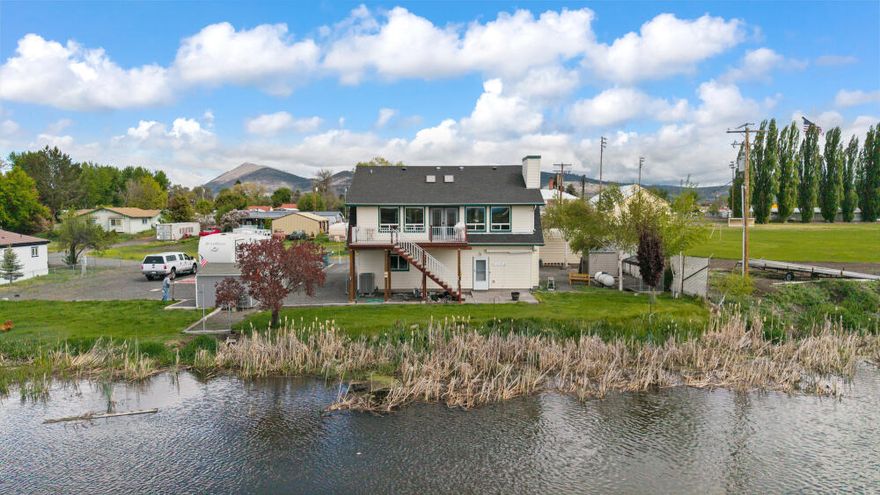 If you've been dreaming of peaceful riverfront living, this charming 3-bedroom, 2-bath home offers a rare blend of comfort, space, and stunning scenery. Enjoy expansive water views, a cozy fireplace, a spacious kitchen with rich cabinetry and a large island, and a versatile lower-level bedroom with its own entry and bath. Step onto the oversized second-story deck—perfect for entertaining or relaxing—with a propane gas supply and water access for easy roof maintenance. The thoughtful floorplan includes a large downstairs utility room connected via an interior breezeway to a finished, heated garage with a mechanical area featuring a metal bar sink and built-in safe. Additional highlights include a second finished garage, a 50 ft. RV pad with full hookups (50/30/20 amps, sewer, and water), a new black composition roof (May 2025), and a recently updated HVAC system. This riverfront gem has it all—schedule your private showing today!