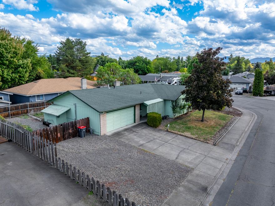 Welcome to 3054 Tahitian Avenue! Located on a large corner lot in a quiet and clean neighborhood, this 3 bedroom, 2 bath home features 1,296 Square Feet. The comfortable floor plan includes a welcoming living room with a wood stove, creating a warm and inviting atmosphere. Also within the home, you'll find a primary bedroom with bathroom, two more bedrooms, a hall bathroom, kitchen and dining area, and laundry located just inside the garage. The home and property also include a 2 car garage with storage room, back deck with a gazebo, garden beds, room for RV parking and storage. Conveniently located just minutes from shopping, dining, medical facilities, the Medford International Airport, and more. Don't miss out on this one, come see it today! Seller will give a $5,000 credit to buyer for flooring and cosmetics with an acceptable offer.