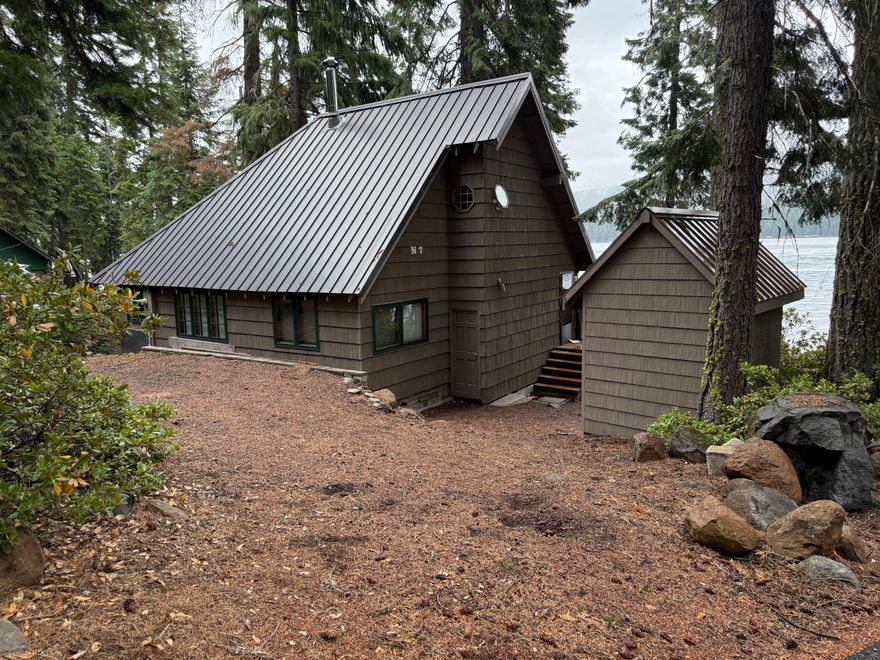 Unique West Side 3 bedroom, 1 bath custom with composite deck and dock.  Asphalt paved driveway and excellent parking provide unusual access. THIS IS NOT A FIXER UPPER.  It is lake front living at its best.  The cabin is completely remodeled and is being sold furnished.  A wall of glass in the living room provides outstanding views of the lake.  Granite counter tops in the modernized kitchen, wood floors, and a wood stove provide complete comfort for your stay.  Treat yourself to a personal tour of this beautiful offering.