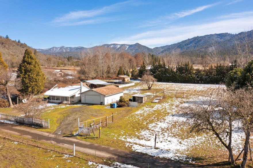 Situated in a serene country setting on 2 acres, you'll find this 2 bedroom, 1 bath country cottage. Some of the interior features of this home are a large living area, with kitchen and dining adjacent, and a large primary bedroom. The large covered front porch provides a great spot to sit back and enjoy the mountainous scenery. Next to the house is a 36' X 24' double car garage that allows plenty of room for parking, projects, and storage. In the fenced pasture, you'll find the horse stables and corral. There is plenty of room for your horses or other farm animals on the property. Grants Pass Irrigation District supplies irrigation water throughout the summer to keep your pasture and yard green. This home is set back a half mile from East Evans Creek Road on a private shared drive. Located only 5 minutes north from the town of Rogue River.