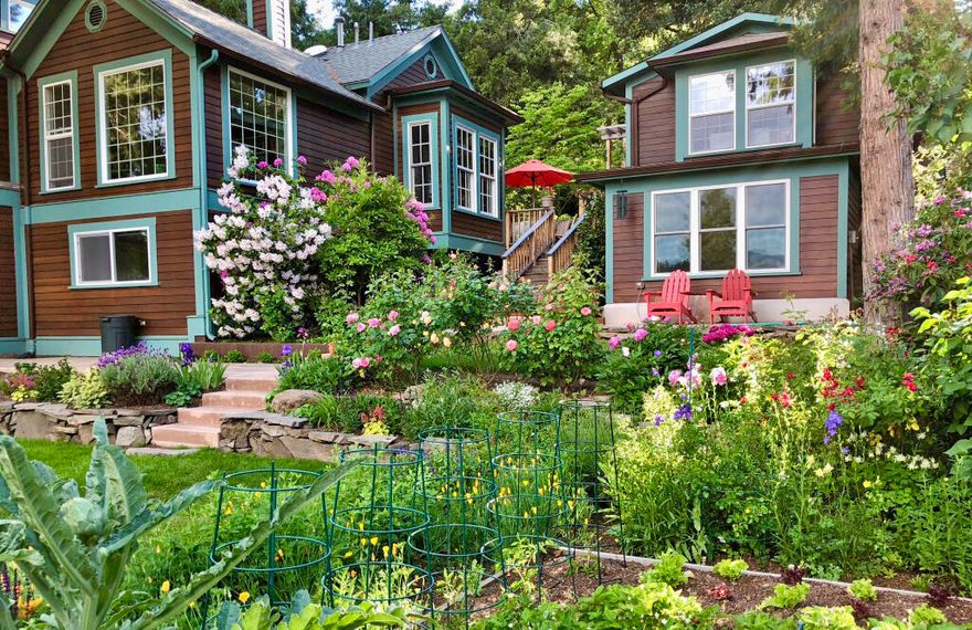 Charming and thoroughly updated home with detached guest cottage on a third-acre with stunning gardens and park-like landscaping; all within a half-mile radius of downtown! Recent renovations include new limestone tile floor in kitchen, new appliances, natural quartzite counters, totally updated main-level primary en-suite and three additional full bathrooms, radiant-heated tile floors, custom cabinets, media room with mountain views, and new gas fireplace with stone hearth. Lower level of main home has two guest bedrooms, full bath, and family room with access to deck and hot tub. Fully permitted detached cottage (ADU) with ground floor  kitchen cooktop and refrigerator, upper level bedroom suite with full bath, and 2-car garage. Grounds feature mature evergreens and plantings, TID irrigation rights, greenhouse, decks, concrete patios, and a serene water feature with natural boulders. Inquire with agents for documentation of improvements, disclosures, tile information, and maps.