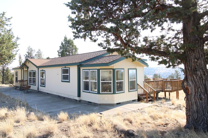 Spacious, well maintained home and shop on over 5 acres with amazing Cascade Mountain views. This light and bright ranch style manufactured home has 3 bedrooms, 2 bathrooms and plenty of space for the entire family. The home features 2 living spaces with vaulted ceilings, including a family room and living room. The kitchen, w/ breakfast bar opens to both the dining nook and living room with a cozy wood burning stove and large windows that bring in natural light and showcases the fantastic mountain views. There is a spacious primary bedroom with two large closets and large ensuite bathroom  w/ soaking tub as well as 2 additional bedrooms & attached laundry room leading to the back deck. Outside, you'll find plenty of space for entertaining while enjoying the best views in the neighborhood on the wrap-around deck. There is also a 24'x48'  garage/shop with a fully finished and insulated 24'x16 studio w/ it's own entrance. Come see this Prineville gem for yourself!