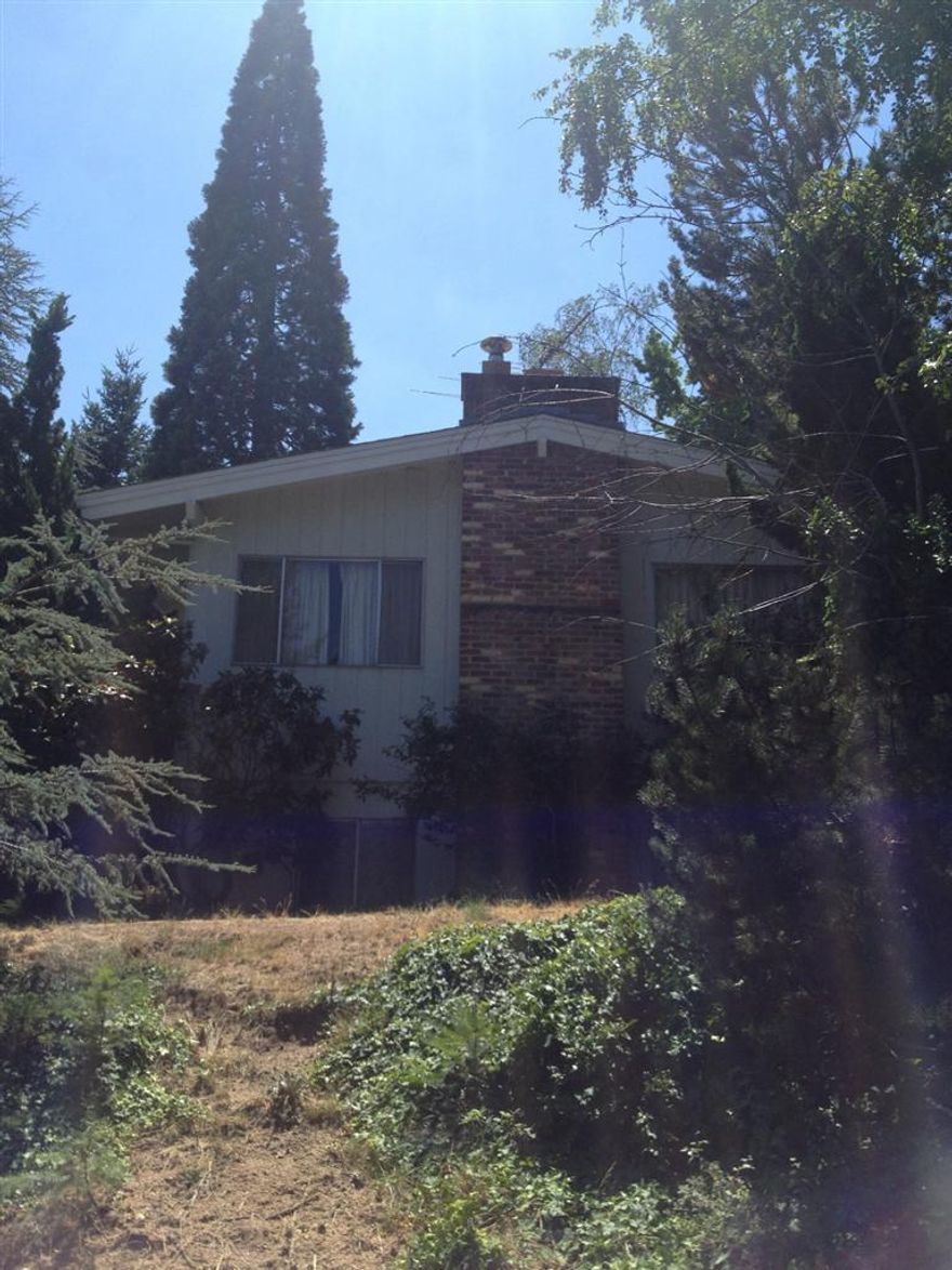 Searching for a home with potential? Search no further. This home could really shine with some day modern touches. This spacious home boasts exposed beam vaulted ceilings in the living, dining, kitchen and main floor bedrooms. Lovely original hardwood floors, a cozy fireplace, 4 bedrooms, and 2 baths. Great views of the mountains from the living room, a private backyard with mature landscaping, covered patio, and loads of wildlife and birds! There is a one attached garage and an additional 2 car off-street parking bay. Conveniently located above Southern Oregon University and only a 25 minute walk to the heart of downtown Ashland (or a 5 minute drive). This home to be sold as is and is priced accordingly. Home has never been abused, but has had very little updating over the years.