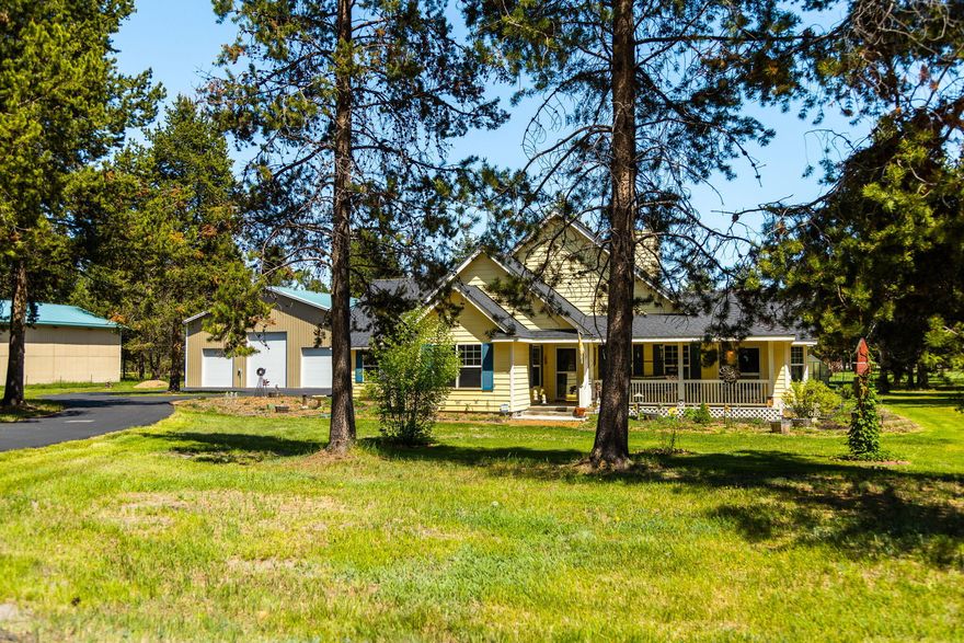 Introducing a picturesque, sunlit farmhouse with remarkable curb appeal & an inviting wrap-around front porch. Situated on a meticulously landscaped 1-acre property, this residence boasts a paved circular driveway & a generous 40 x 50 workshop. A two-sided fireplace graces both the cozy living room & the well-appointed kitchen. The primary bedroom is a true sanctuary, featuring a spacious walk-in closet, a door leading to the back deck, & an en-suite bathroom with a shower & a luxurious soaking tub. The backyard is securely enclosed with a fence, & you'll find a greenhouse & a woodshed for your gardening needs. The impressive shop is a standout feature, boasting insulation, wiring with a 50-amp service, & an additional loft for storage. This idyllic package is set against the backdrop of a charming paved street in the highly sought-after Lazy River South community. Plus, enjoy easy access to the Deschutes River & the Quail Run golf course, just a stone's throw away.