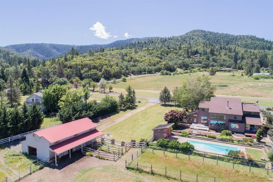 Views abound from this horse lover's dream on 5+ acres w/seasonal creek. Adorned by mature landscaping & colorful flowers, this home offers an inviting front entry. Step inside and bask in breathtaking views through two-stories of windows from the sunken living rm w/soaring ceiling & wood-burning stove. The upgraded kitchen offers a dining area, breakfast bar, granite counters, & farmhouse sink w/reverse osmosis. Just off the kitchen is the 12x16 sunroom w/double-door entry, tile floor, & sink. The main floor master features its own deck, 2 closets, built-in dresser, & ensuite w/ large shower, jetted tub, & 2-sink vanity. The upstairs has a loft area w/storage closet & built-in desk, 2 guest bedrooms & full bath. The backyard boasts endless views, in-ground pool, & 16x8 pool house w/full bath. Beyond the pool house, a walkway leads to the 30x40 insulated barn w/4 stalls, misters, 20' tack room, 15-ton hayloft, & access to the round pen & pasture, surrounded by 5' no-climb horse fence.