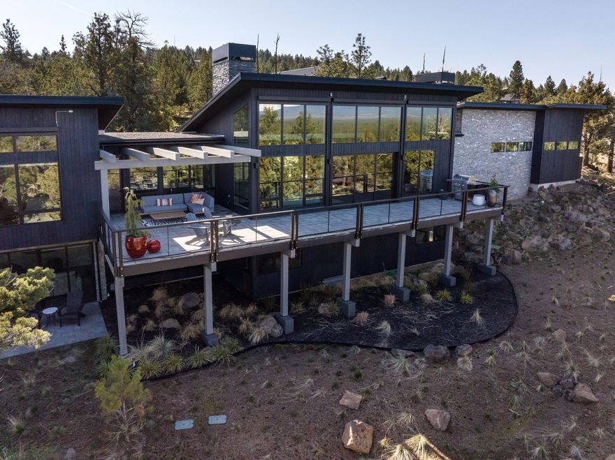 Nestled in the prestigious North Rim community, this luxurious home offers breathtaking panoramic views of the Cascade Mountains, visible from the moment you step inside. Expansive 12-foot sliding glass doors frame vistas from Mt. Bachelor to Mt. Adams, perfectly blending nature with modern elegance. The great room features a sleek Isokern gas fireplace, while the gourmet kitchen impresses with a 12-foot leathered quartzite island, high-end appliances, and thoughtful design for effortless entertaining. The main level also includes a refined office with custom built-ins and a serene primary suite with a private sitting room, dual-sided fireplace, spa-like ensuite, and his-and-hers walk-in closets. The lower level features two bedrooms, a bonus room with built-ins, quartz countertops, wine cooler, and patio access. The oversized garage includes epoxy floors, a work station, dog wash, and mechanical room. Residents enjoy access to a private lodge, tennis/pickleball court, and parkland.