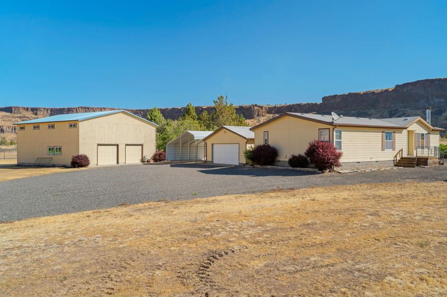 This adorable 3 bedroom 2 bathroom home on 2 acres near the quiet end of Horny Hollow has it all. 1404 square feet of living space includes a spacious primary ensuite, open living room with propane fireplace, kitchen with a pantry and breakfast bar, and vaulted ceilings over a bright living area. Outside you'll find a detached garage with opener, a dual carport for parking or storage, AND a 1600sqft shop with 2 roll-up doors and a bonus space upstairs. This groomed 2-acre property has a huge gravel turn-around for trailers or RVs, and panoramic views of the rock wall across the river canyon. Established orchard is ripe with apples and pears, and fenced to keep the deer out. Chicken coop out back is ready for your flock! Did I mention this property backs up to public lands?! Bring your DIY kit or contractor to upgrade the home to your liking. Whatever you do, don't wait to secure this incredible value in Crooked River Ranch's most sought-after corner!