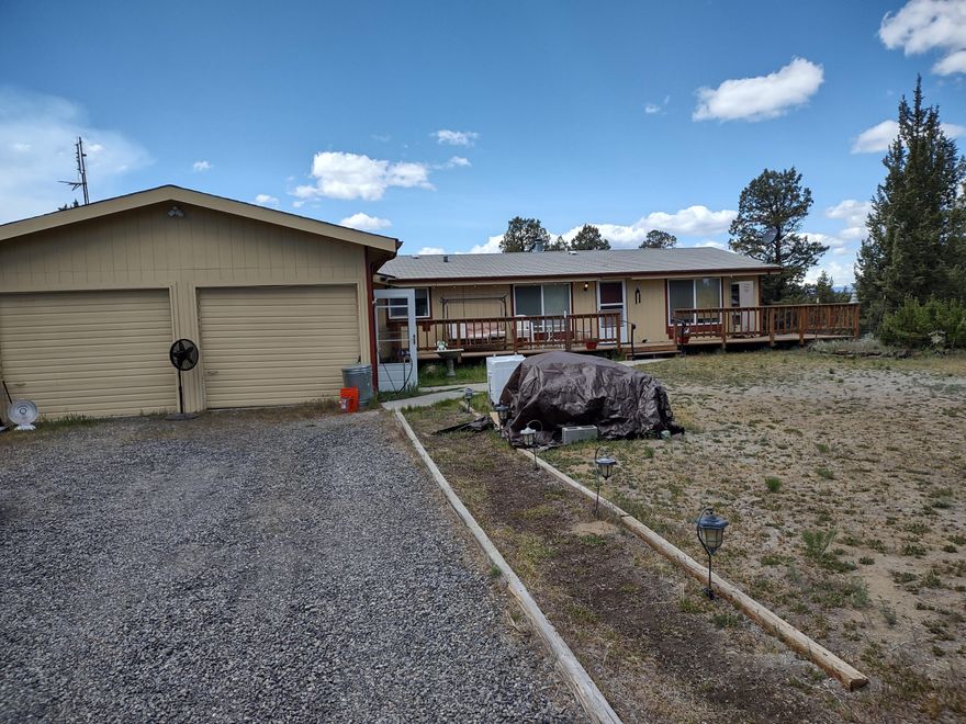 Solid 3 bedroom, 2 bath home with 2 car garage. Split floor plan, open kitchen and decks in both front and rear. Large 1,000+ sq ft shop building with high roll up door, mezzanine storage area, plus ground level separate office. Paved road, close to entrance of ''The Ranch'', mountain views and plenty of parking space. Well re-drilled and new pump within the past 5 years. Owner is retiring and moving on.