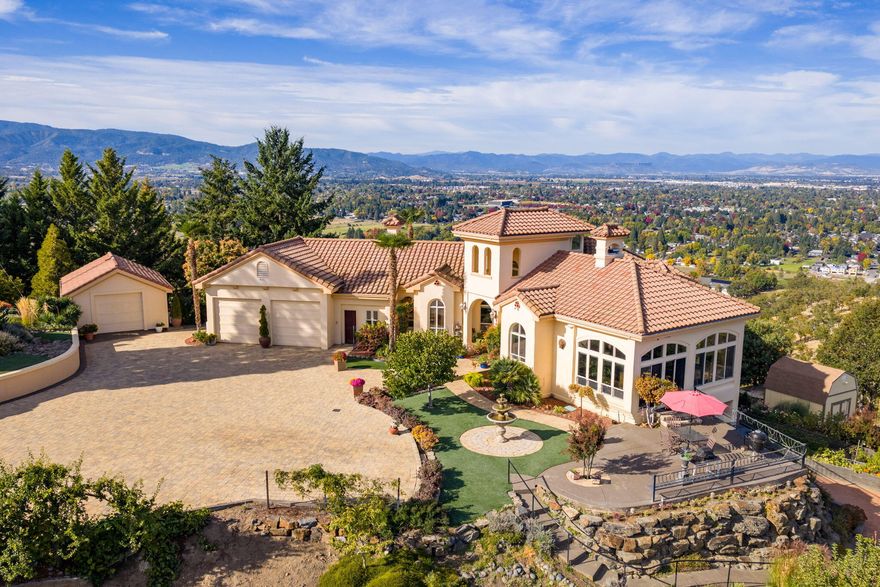 Just Listed! Amazing Northwest Santa Fe style home perched on a knoll w/forever views overlooking vineyards, valley, city lights & Mts. Paved driveway to 1.02 ac lot w/brick entrance wall w/dbl gated entry to paver courtyard w/3 car garage, stucco exterior, tile roof, palm trees & great landscaping w/night lighting + a lg water fountain. Lg front arched wood door w/covered area w/beautiful brick floors, Lg ceilings, archways niches, floor to ceiling windows to take the views! Many doors & French doors to beautiful cement patios off primary suite, great/family rm & dining rm. Downstairs 2 bdrms w/lg cement patio + a brick covered patio. Montana stone sitting area w/built-in fireplace. Amazing kitchen w/lg island, granite counters, Wolfe 6 burner gas cooktop & oversized convection oven perfect for entertaining. Beautiful primary suite, 2 walk-in closets, lg tile shower, soaking tub & French doors out to a covered patio. Many garden beds w/drip systems, greenhouse & whole house generator