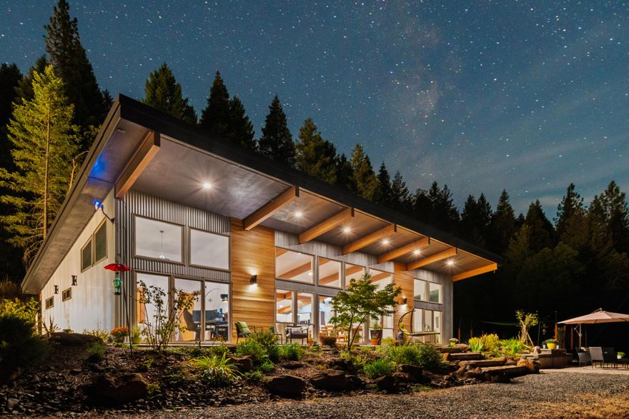 *Assumable interest rate of 4.403%!!!* Inquire for more details.
2021-built custom home at 24100 E Evans Creek Rd, Central Point—21 acres with creek frontage and pure privacy. You have to see this modern masterpiece with 15' vaulted ceilings, exposed beams, and massive windows framing forest views. Warm up by the custom wood stove or cook in the gourmet kitchen with Bosch appliances and double ovens. Hardwood/tile floors, heated bathroom floors, and walk-in showers add luxury. The large master bedroom is simple, cozy and luxurious. The windows look up into the stars at night. A finished ADU (converted garage) suits family or guests. Or it can be reconverted for additional parking. Outside, a fenced garden, meadow, RV hookups, and 18x6 swim spa offer endless outdoor living, with a seasonal creek and panoramic views. Starlink internet keeps you connected. This turn-key sanctuary is built for those craving space and freedom. Hiking, hunting or just enjoying the peace.