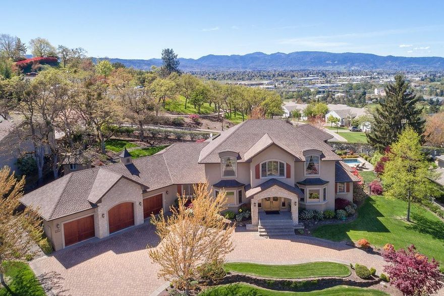 GORGEOUS custom home in serene location w/ exceptional quality, extras & amazing views yet in the heart of Medford convenient to all your needs! Exterior of stucco & sandstone from Idaho opens to 3 bed, 3 full & 2 half baths, 5649 sq ft of soaring ceilings, Italian Versace tile, hickory hardwood floors, honey dipped stained knotty alder woodwork & trim, 4 different fireplaces, abundance of windows for views and light & a floorplan that lends itself to large group entertaining or intimate, relaxing time for two. The gourmet kitchen is in the center of the home & allows easy preparation of your favorites while still visiting with friends & family. Main floor living w/luxurious master suite, laundry, private den/office, great rm, formal & informal dining & easy access to outdoor fp living, pool, waterfalls, gardens & Views. Upstrs boasts 2 guest suites,2nd office & another living/pool table, bar area w/2nd outdr living VIEW area. Main flr closet for future elevator to 2nd flr. 3 car gar.