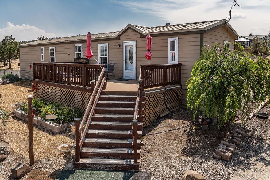 Nicely updated 3 bed, 2 bath manufactured home on 1.88 acres w/ 924 sq ft of comfortable living space. Recent upgrades include a new roof, remodeled bath, updated flooring, windows, skylights, Heat Pump/AC, Hardy plank siding, and new hot tub. Enjoy the peaceful setting w/ 12x24 front deck, paver patios, walkways, water feature & fully fenced garden area. Flower beds & fruit trees are supported by drip system for easy care. Bonus art studio/loft, RV shed, detached carport and shop with 220 power. 2 container buildings for storage included. Fully fenced & gated w/ circular drive landscaped for low maintenance & good defensible space. A perfect blend of function charm and privacy.