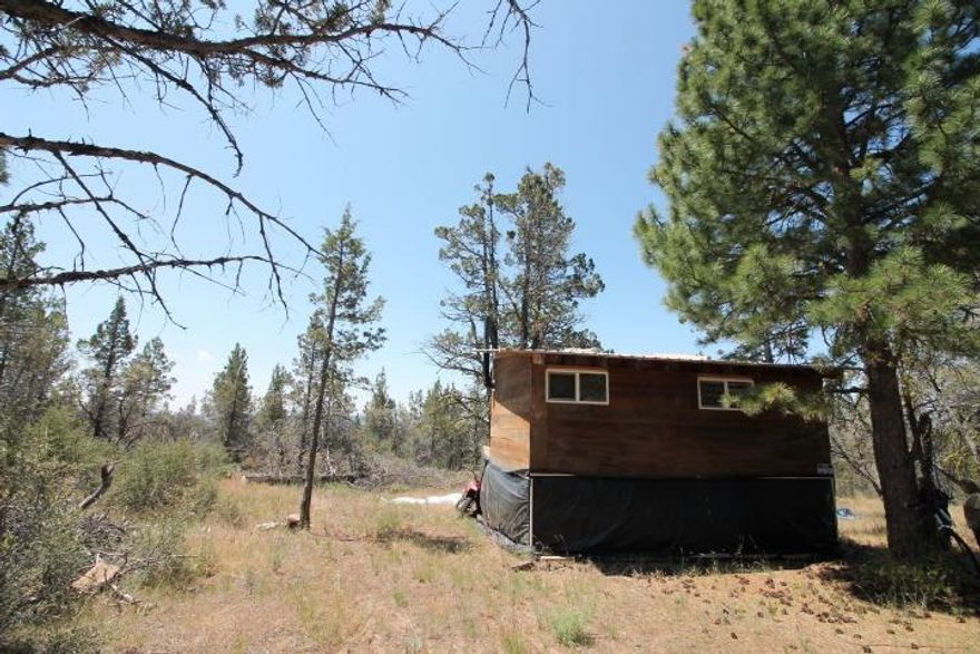 : Very nice parcel of land that has a cabin constructed on it. Cabin is made from California Redwood. Has vinyl windows and a small deck. Raised up off the ground for extra storage underneath. View of the valley below.
