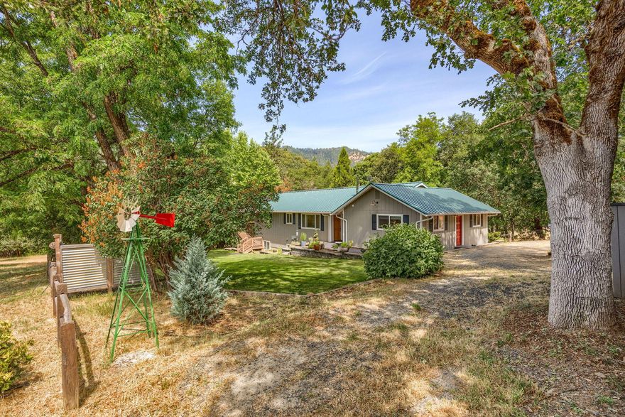 Beautiful private location on 10.82 acres w/fruit trees, pasture, fence garden and many outbuildings including a 40x20 3 car carport, 24x24 shop/garage, large old barn, chicken coop and tool shed. Separate office/studio w/vaulted ceilings, insulated w/mini split HVAC, covered patio and a deck overlooking garden area. Property sits behind rolling Hills of Del Rio Vineyard. Home was completely built from the studs in 2006! Recent updates include exterior paint, shutters, stone countertops, mini split's, flooring, stainless steel appliances, including refrigerator. Open floor plan to great room w/vaulted ceilings and certified wood stove. Beautiful large covered deck to enjoy the views! Main floor has 3 bedrooms, 2 primary suites, 1 w/walk-in closet and soaking tub. 3rd bedroom + downstairs a separate 1/1 living quarters w/large covered patio and exterior door into living room, mini kitchen, wet bar and walk-in pantry that can be a great set up for extra living or perfect in law set up.
