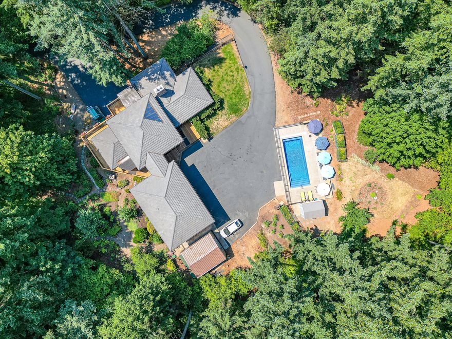 Breathtaking setting on 4+ park-acres near McKenzie River! This private, custom built home nestled in the trees spans 3,815 sqf of living space and 4.1 acres of fully fenced serene outdoor space.  The main level has a remodeled kitchen with new appliances, two dining area, large living room with propane fireplace and office with woodstove. Upstairs you'll find the primary suite with balcony and skylights looking out among the trees., 2 more large bedrooms and full bath. Opportunities are endless in the finished basement/gym/workshop with separate entrance. Additional features include new fireproof concrete tile roof & gutters, A/C,heat pump, new in-ground pool with automatic cover and awning, General Steel insulated shop/garage, Cummins generator (can power property for up to 7 days), security system, indoor hot tub room, multiple garden areas including an English Garden, Rhododendron Garden, Rose Garden, & fruit/vegetable Garden, bark trail system, and much more.