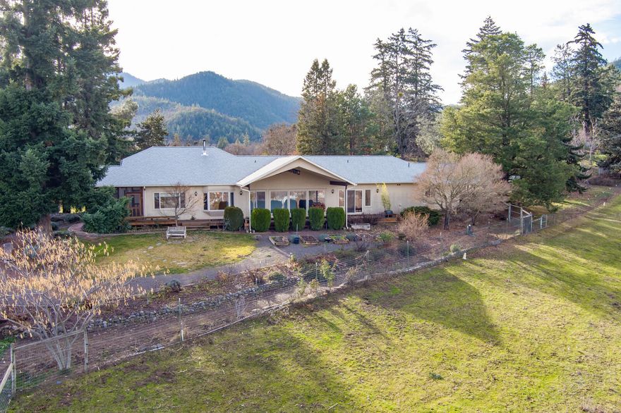 Peaceful setting with panoramic views, wonderful land for gardening, pets and tranquil country living.  Single-level home w/solid wood and tile flooring throughout, master suite w/ 2 walk-in closets, galley style kitchen w/ quartz counters, tile backsplash, walk-in pantry & a whole house water filtration system.  Window-lined living room, screened porch w/ ceiling fan & lighting, enclosed spacious sunroom, cozy office, laundry room, 2nd bedroom & hall bath complete the main house.  The attached guest quarters & bath provides the third bedroom with it's own private entrance.  Plenty of covered parking options with a 2-car attached garage, a separate detached garage and a separate covered RV garage w/hookups.  The property is zoned EFU and has TID irrigation rights, outbuildings, fruit trees, Koi pond, raised garden beds, barn, riding arena, five separate-fenced pastures & a greenhouse.  Propane powered backup generator & a backup 5000 gallon water storage tank.