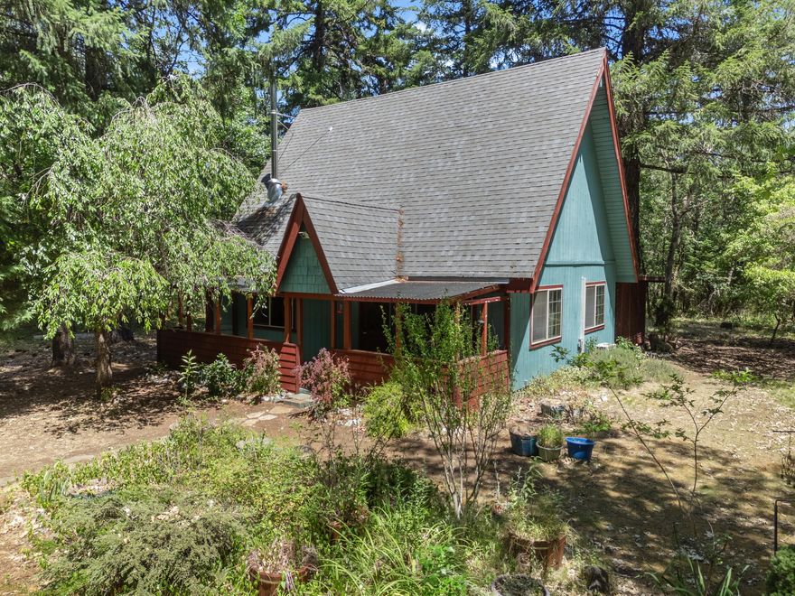 Sweet Cottage in the Woods! This is a great starter home just under 1200 sq ft with 2 Bedrooms and 2 Baths on 5.09 acres of useable land! 2 separate suites, one upstairs and one downstairs. It has beautiful new flooring throughout. There is a car cover with stacked firewood and lots of space for garden tools. You will also find a large carport area where an RV could stay undercover.  Perfect sized enclosed patio with an awesome jacuzzi! Located in the beautiful Illinois Valley only a few minutes from town and close to the scenic Illinois River.  It's also just over an hour to the beautiful California coast! Come check this one out, you won't be disappointed.