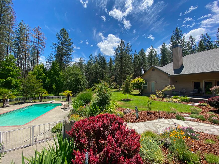 This beautiful 4600+ S/F home rests on a private 5-acre oasis with a resort-like feeling. The incredible landscaping welcomes you with flowering shrubs, lawns, beautiful pool and patio, fenced garden and fruit trees, on 5 level acres that have been selectively cleared of excess trees creating defensible space with rural fire station nearby for peace of mind. Potential for a bed&breakfast, wedding venue or your own private retreat. 3-car attached garage, 1400+ sf shop with mezzanine & 2 large RV size doors, paved circular driveway, and security gated entry. The home has 4 bedrooms and 3 baths all on one level, a bonus room above the garage (pool table included), office, living room with brick fireplace, family room, kitchen with breakfast nook, formal dining room, central vac, and spacious master. The home and property are designed for entertaining with indoor/outdoor sound system . This gem is in a sought-after rural subdivision close to historic downtown Grants Pass!
