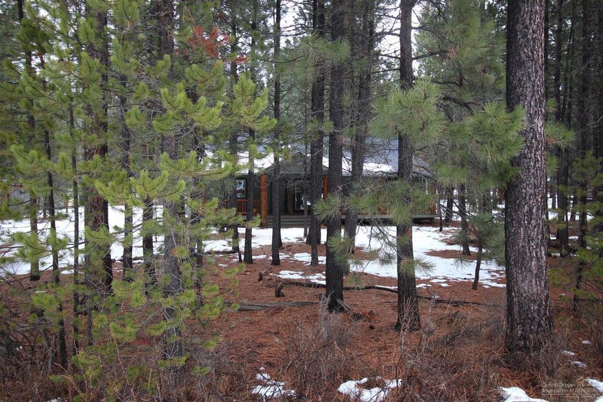 A wooded retreat. Deer, wild rabbits and an abundance of birds visit the treed front yard. Small pond with a bridge. Spacious log front porch. Vaulted great room with log beams, skylights and a propane river rock fireplace. V-G fir French doors to master-suite with a bay window, walk-in closet with built-ins. Large laundry room with a deep sink and a generous pantry. Charming bonus room plus a sun-room with AC and heat. There is also a triple car garage and a fenced back yard. Newer washer and dryer and kitchen appliances are included. Don't over look the great parks in this subdivision for your enjoyment along with easy access to the Deschutes River. The sellers installed new laminate flooring in the living room, master bedroom, dining room, and the hallway the end of January and the beginning of February 2020. The sellers will also give the buyers a $500 credit at closing toward new kitchen counters.